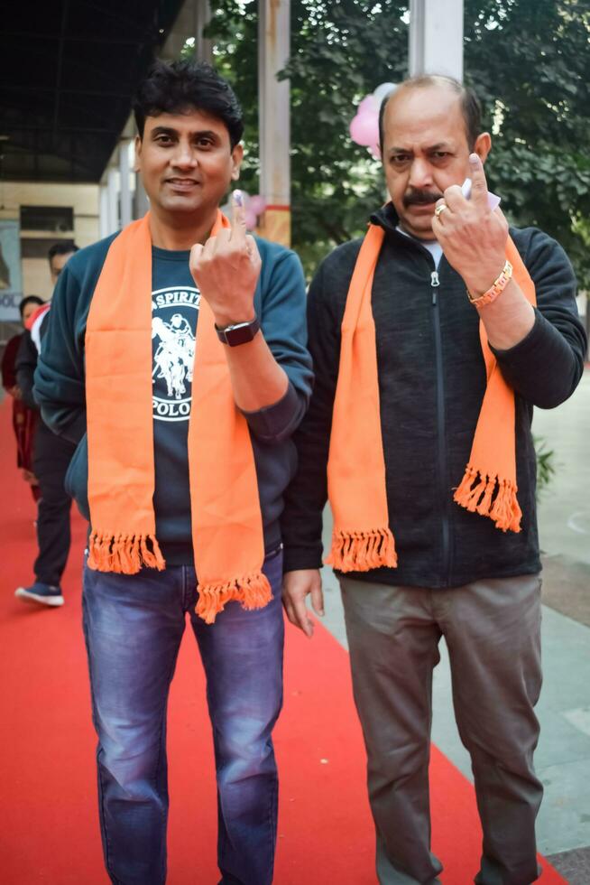 New Delhi, India - March 04 2023 - Unidentified people showing their ink-marked fingers after casting votes in front of polling booth of east Delhi area for MCD local body Elections 2022 photo