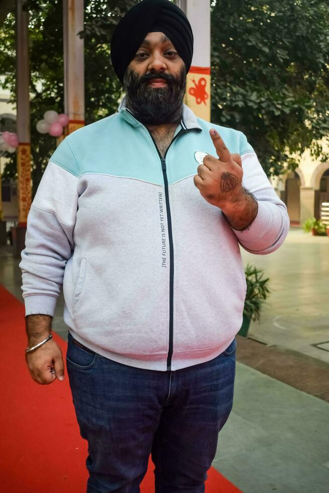 New Delhi, India - March 04 2023 - Unidentified people showing their ink-marked fingers after casting votes in front of polling booth of east Delhi area for MCD local body Elections 2022 photo
