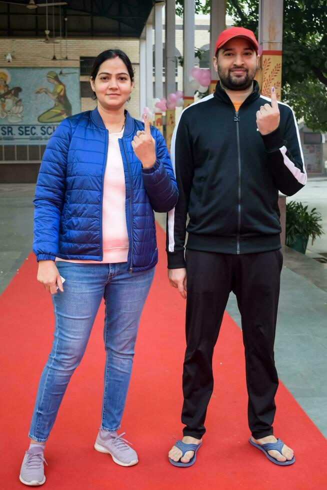 New Delhi, India - March 04 2023 - Unidentified people showing their ink-marked fingers after casting votes in front of polling booth of east Delhi area for MCD local body Elections 2022 photo