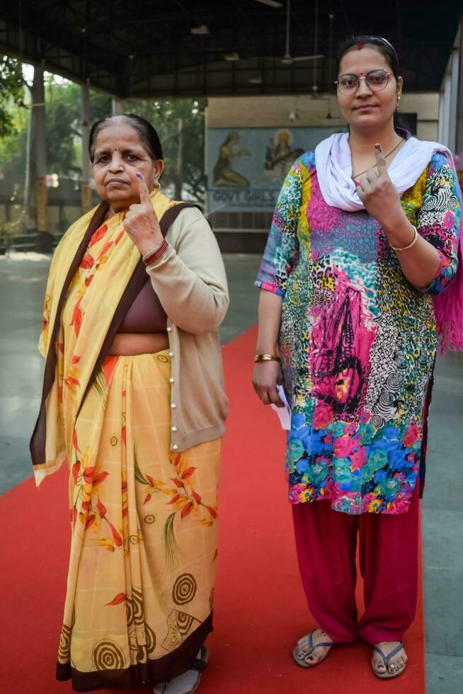 New Delhi, India - March 04 2023 - Unidentified people showing their ink-marked fingers after casting votes in front of polling booth of east Delhi area for MCD local body Elections 2022 photo