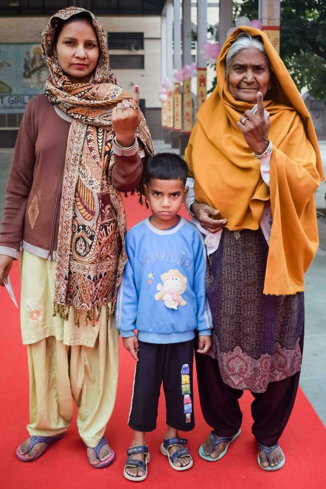 New Delhi, India - March 04 2023 - Unidentified people showing their ink-marked fingers after casting votes in front of polling booth of east Delhi area for MCD local body Elections 2022 photo