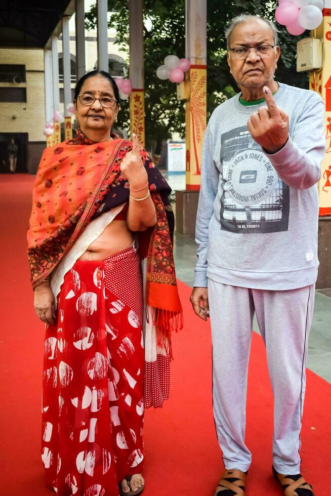 New Delhi, India - March 04 2023 - Unidentified people showing their ink-marked fingers after casting votes in front of polling booth of east Delhi area for MCD local body Elections 2022 photo