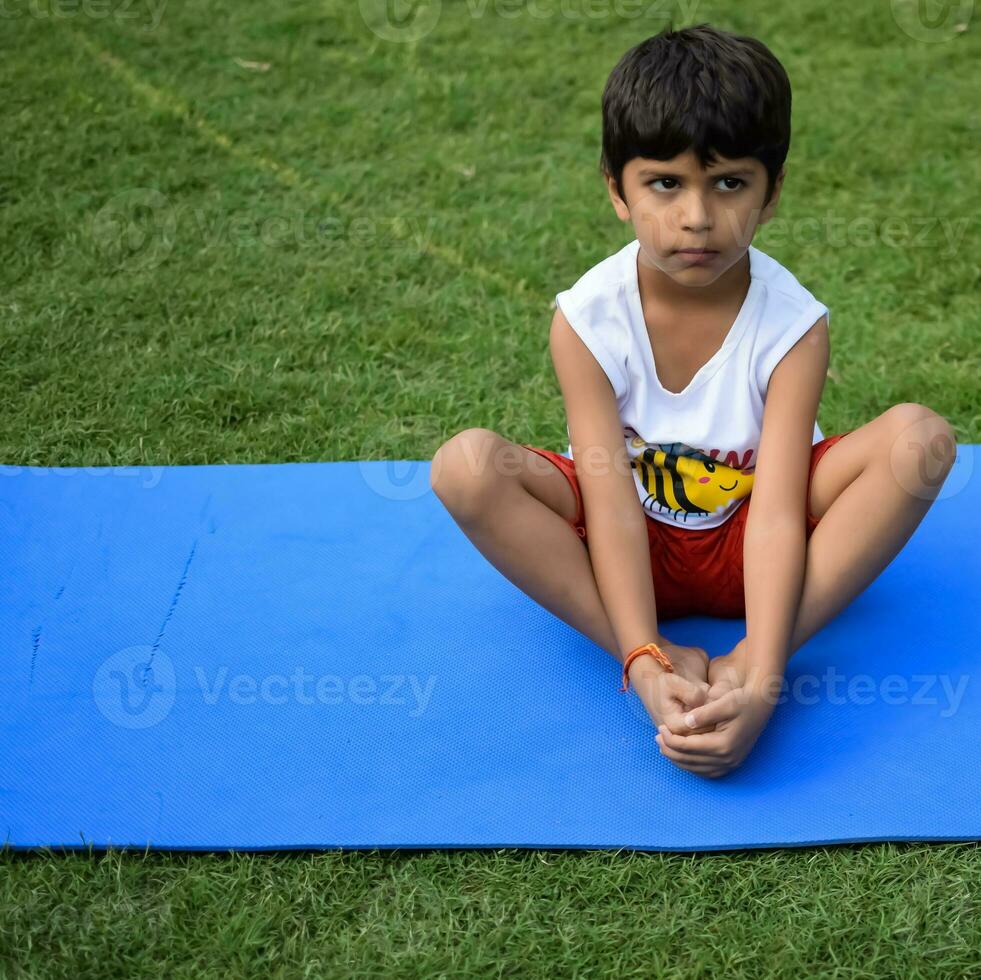 Asian smart kid doing yoga pose in the society park outdoor, Children's yoga pose. The little boy doing Yoga and meditation exercise. photo