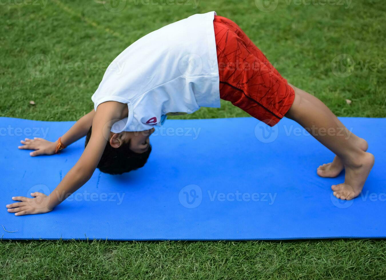 Asian smart kid doing yoga pose in the society park outdoor, Children's yoga pose. The little boy doing Yoga and meditation exercise. photo