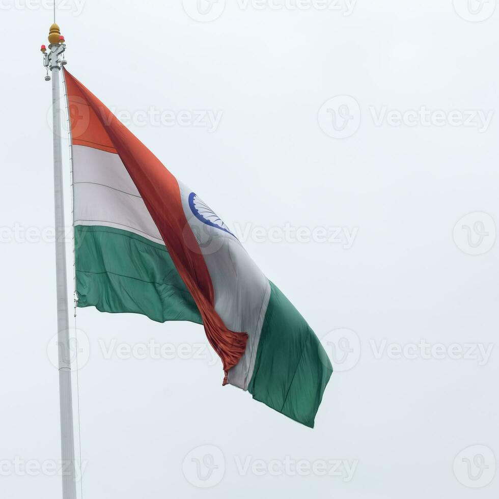 India flag flying high at Connaught Place with pride in blue sky, India flag fluttering, Indian Flag on Independence Day and Republic Day of India, tilt up shot, Waving Indian flag, Har Ghar Tiranga photo