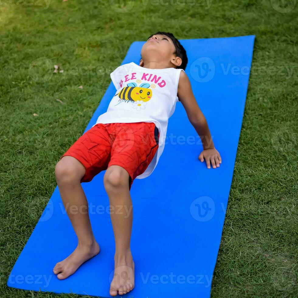 Asian smart kid doing yoga pose in the society park outdoor, Children's yoga pose. The little boy doing Yoga and meditation exercise. photo