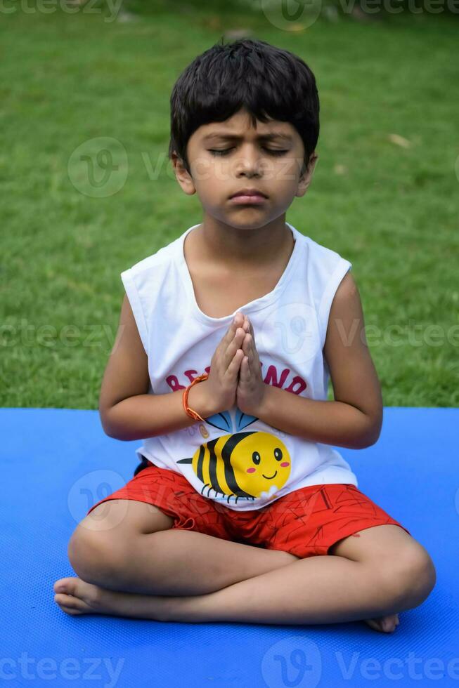 Asian smart kid doing yoga pose in the society park outdoor, Children's yoga pose. The little boy doing Yoga and meditation exercise. photo