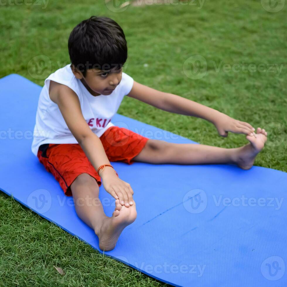 Asian smart kid doing yoga pose in the society park outdoor, Children's yoga pose. The little boy doing Yoga and meditation exercise. photo