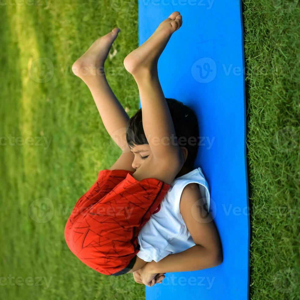 Asian smart kid doing yoga pose in the society park outdoor, Children's yoga pose. The little boy doing Yoga and meditation exercise. photo