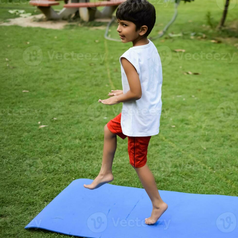 Asian smart kid doing yoga pose in the society park outdoor, Children's yoga pose. The little boy doing Yoga and meditation exercise. photo