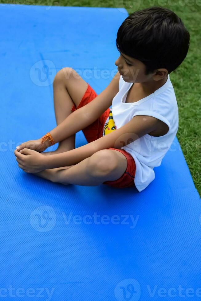 Asian smart kid doing yoga pose in the society park outdoor, Children's yoga pose. The little boy doing Yoga and meditation exercise. photo