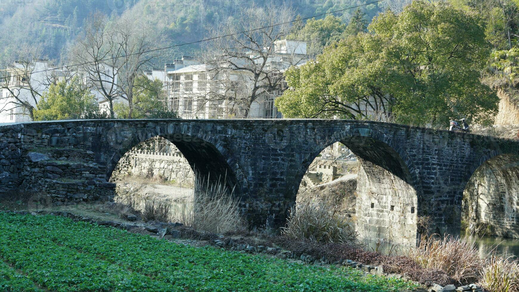 One old traditional Chinese village view with the old arched stone bridge and old wooden buildings in the Southern countryside of the China photo