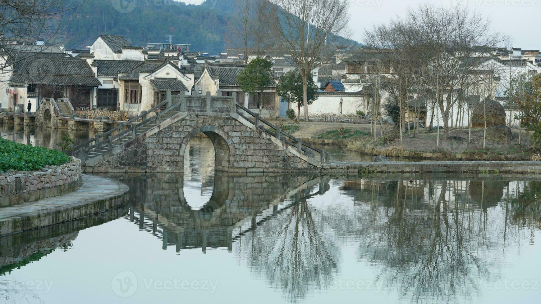 One old traditional Chinese village view with the old arched stone bridge and old wooden buildings in the Southern countryside of the China photo