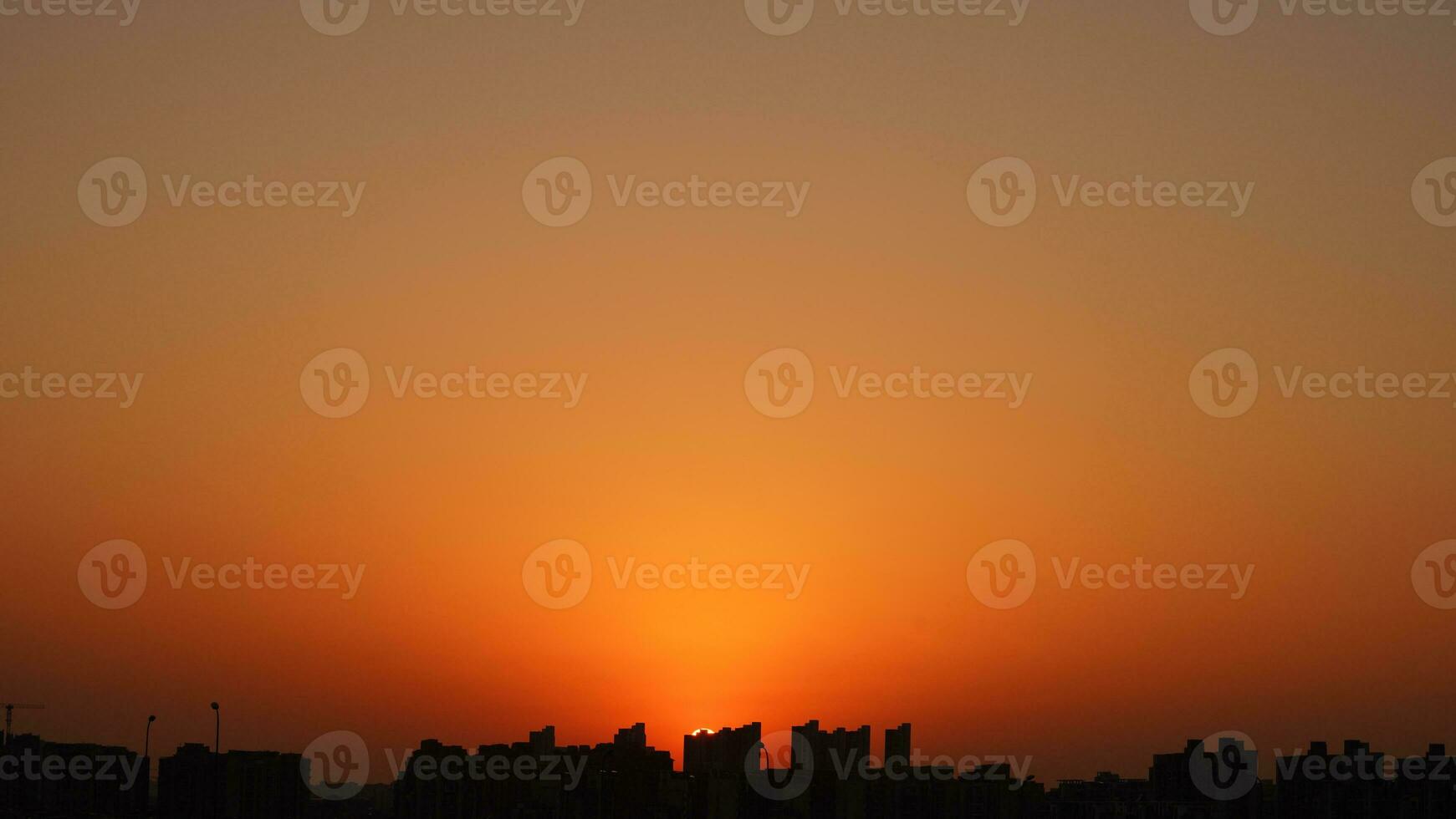 The beautiful sunset view with the buildings' silhouette and orange color sky as background in the city photo