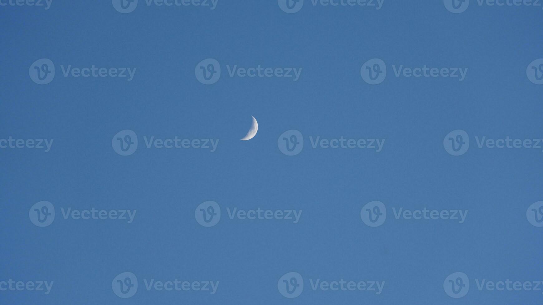 The blue sky view with the curve white moon in the sky in the day photo