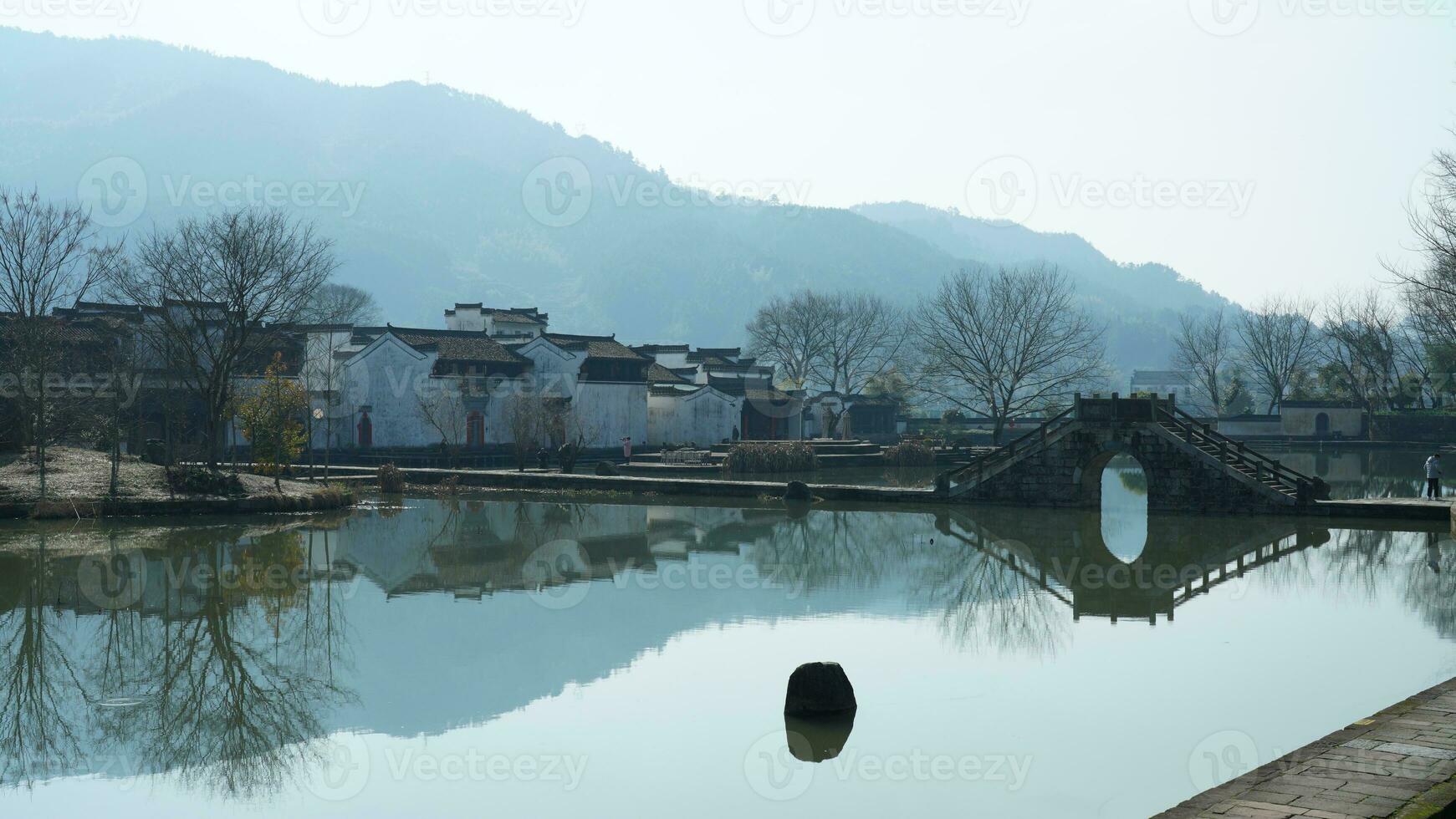 One old traditional Chinese village view with the old arched stone bridge and old wooden buildings in the Southern countryside of the China photo