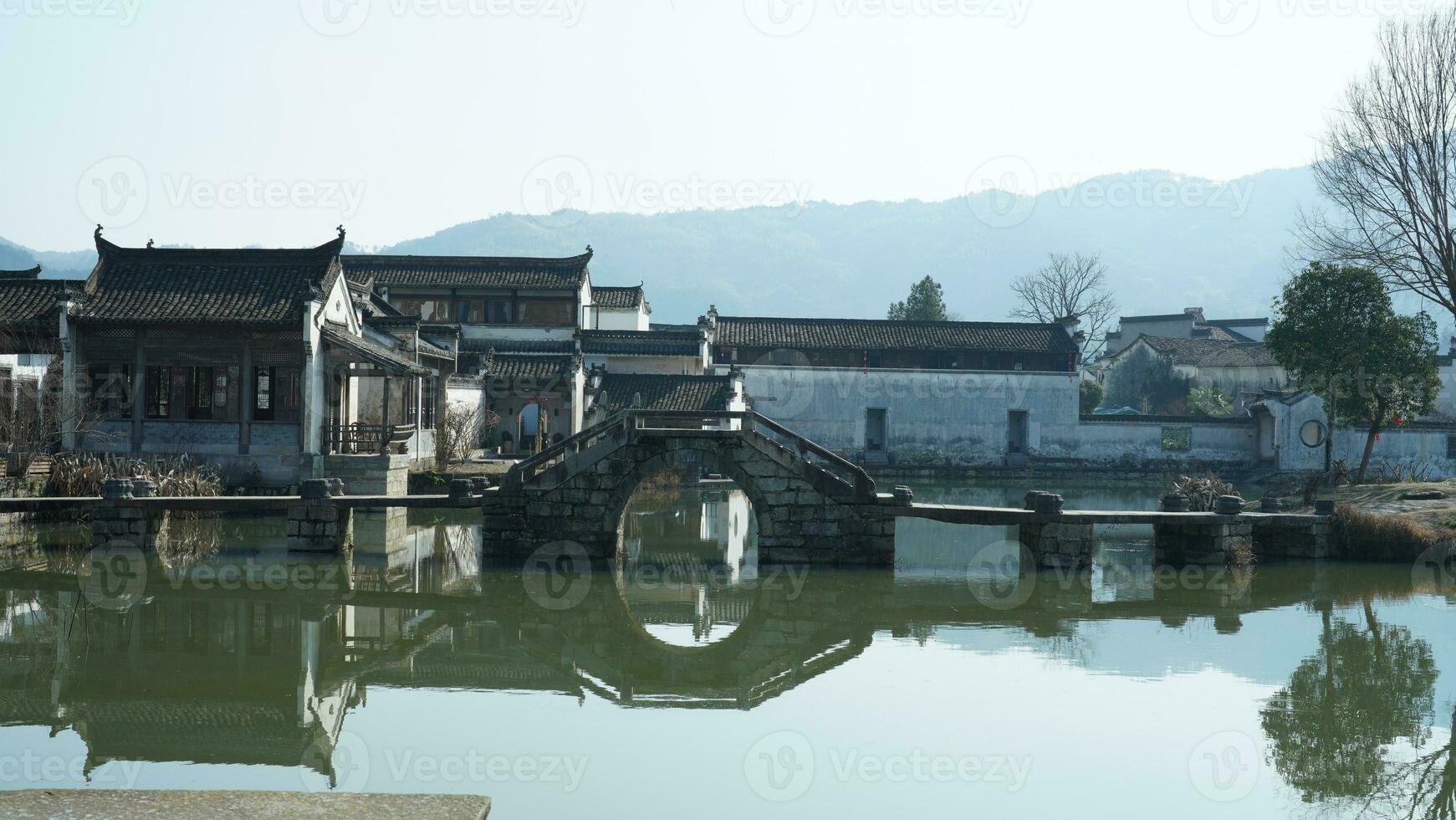 One old traditional Chinese village view with the old arched stone bridge and old wooden buildings in the Southern countryside of the China photo