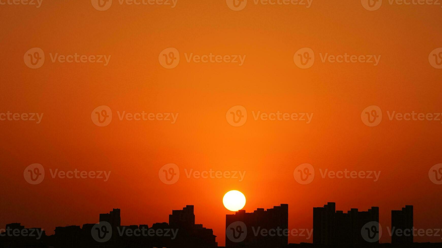 The beautiful sunset view with the buildings' silhouette and orange color sky as background in the city photo