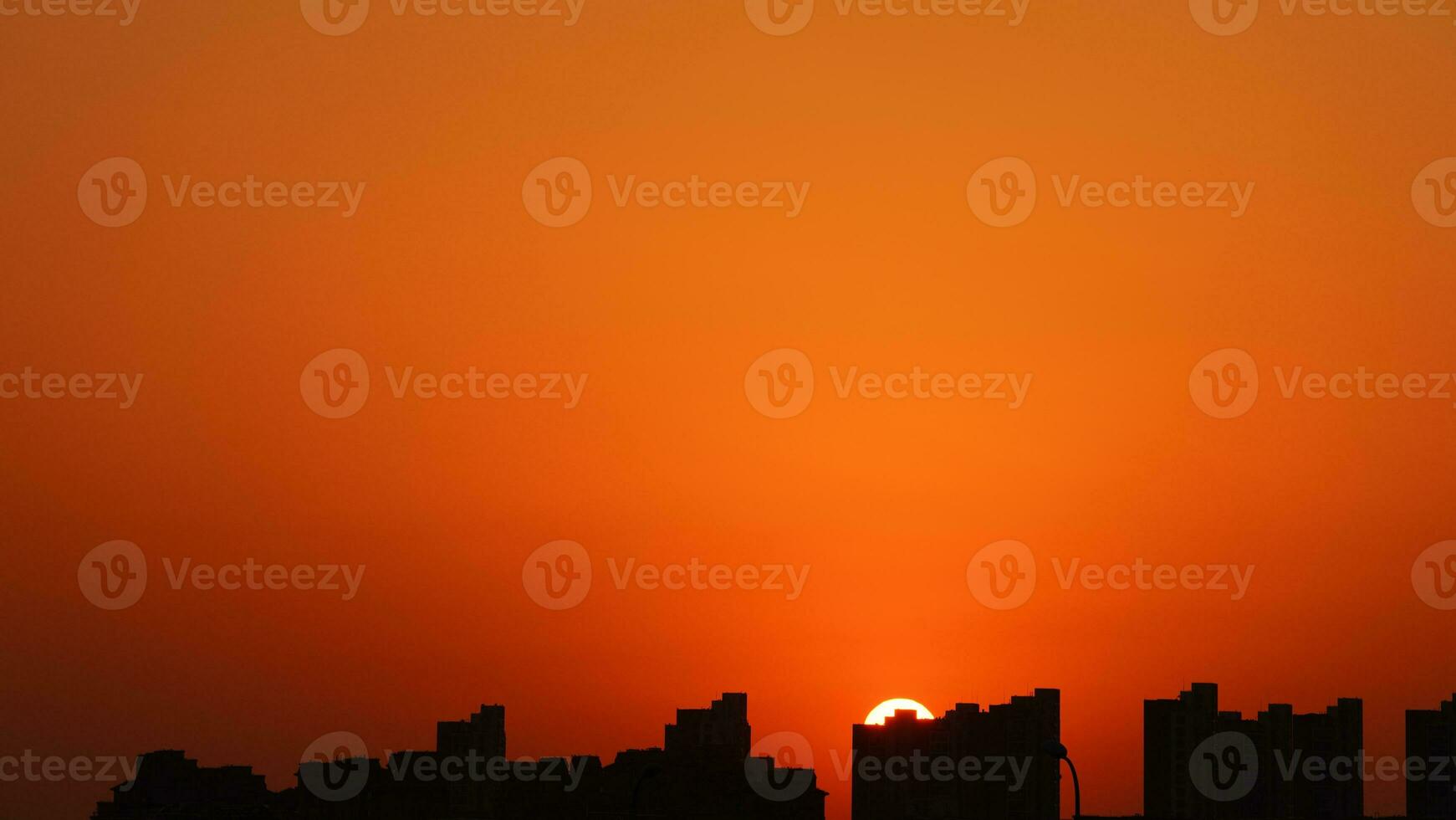 The beautiful sunset view with the buildings' silhouette and orange color sky as background in the city photo