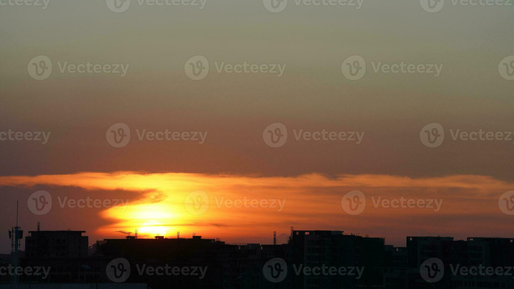 The beautiful sunset view with the buildings' silhouette and orange color sky as background in the city photo