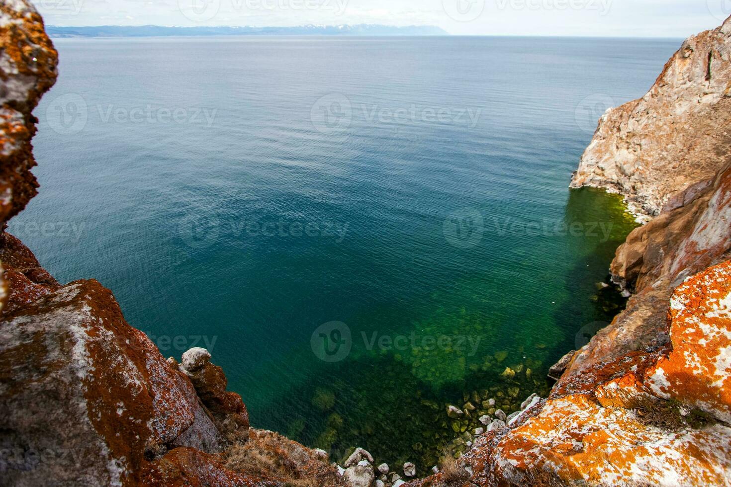 ver de lago baikal con verde transparente agua desde un acantilado. el rock es cubierto con rojo musgo. soleado. foto