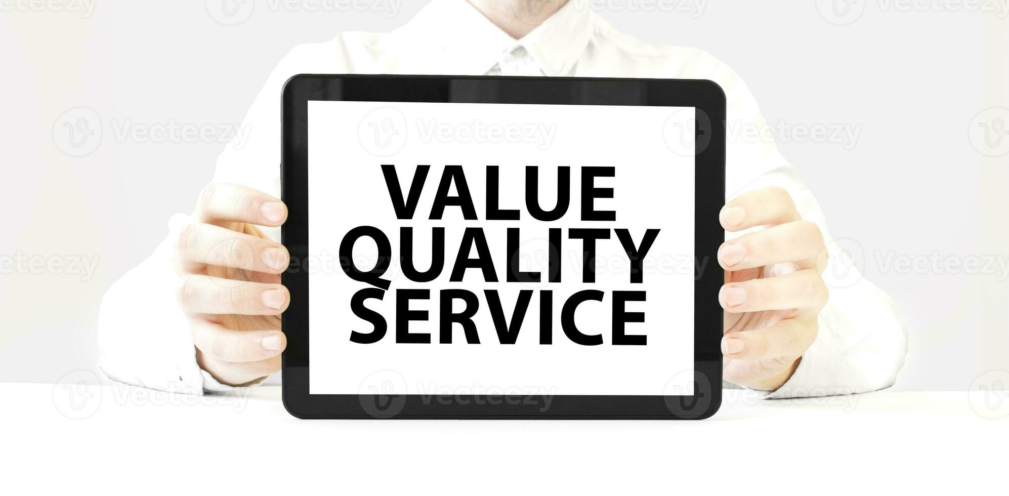 Text value quality service on tablet display in businessman hands on the white background. Business concept photo