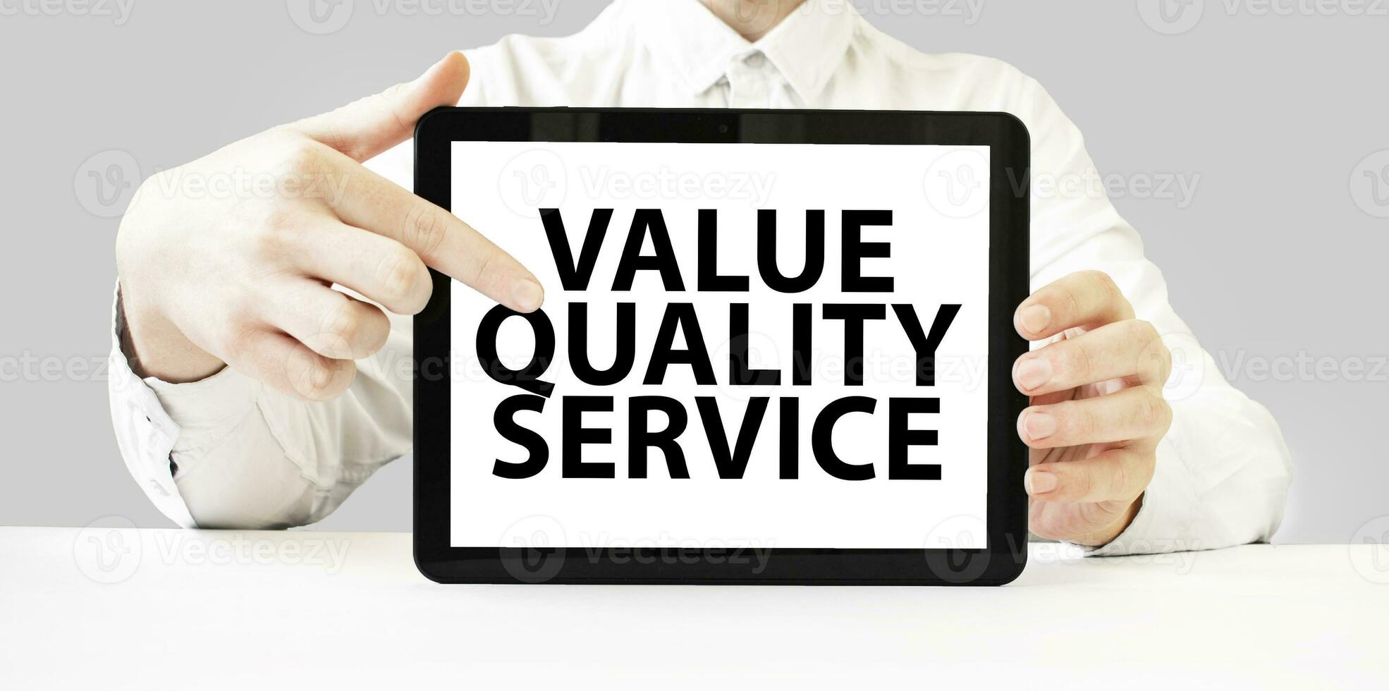 Text value quality service on tablet display in businessman hands on the white background. Business concept photo