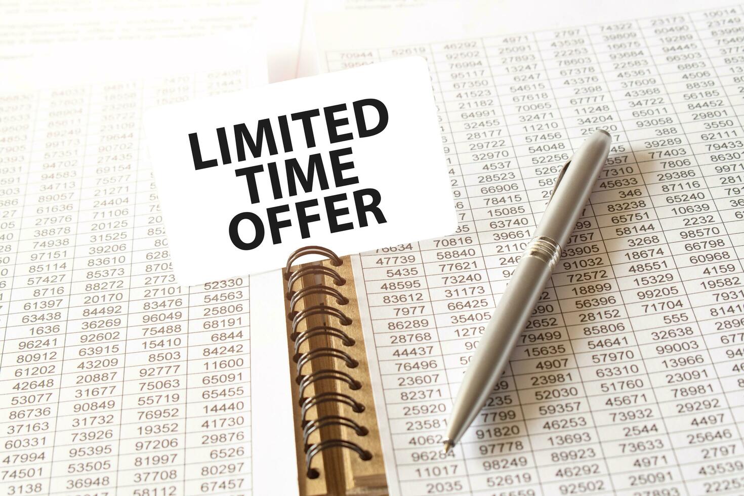 Text LIMITED TIME OFFER on paper card, pen, financial documentation on table - business, banking, finance and investment concept. close up of stock market chart. photo
