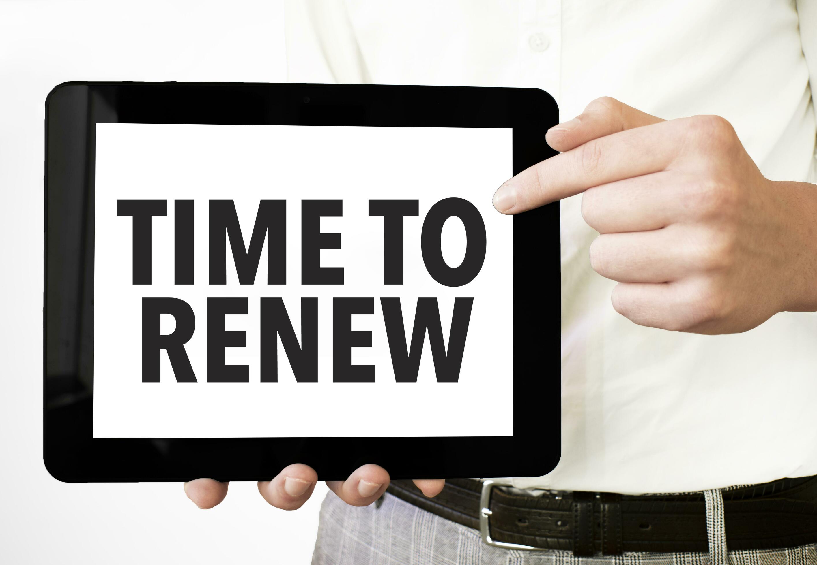 Text time to renew on tablet display in businessman hands on the white