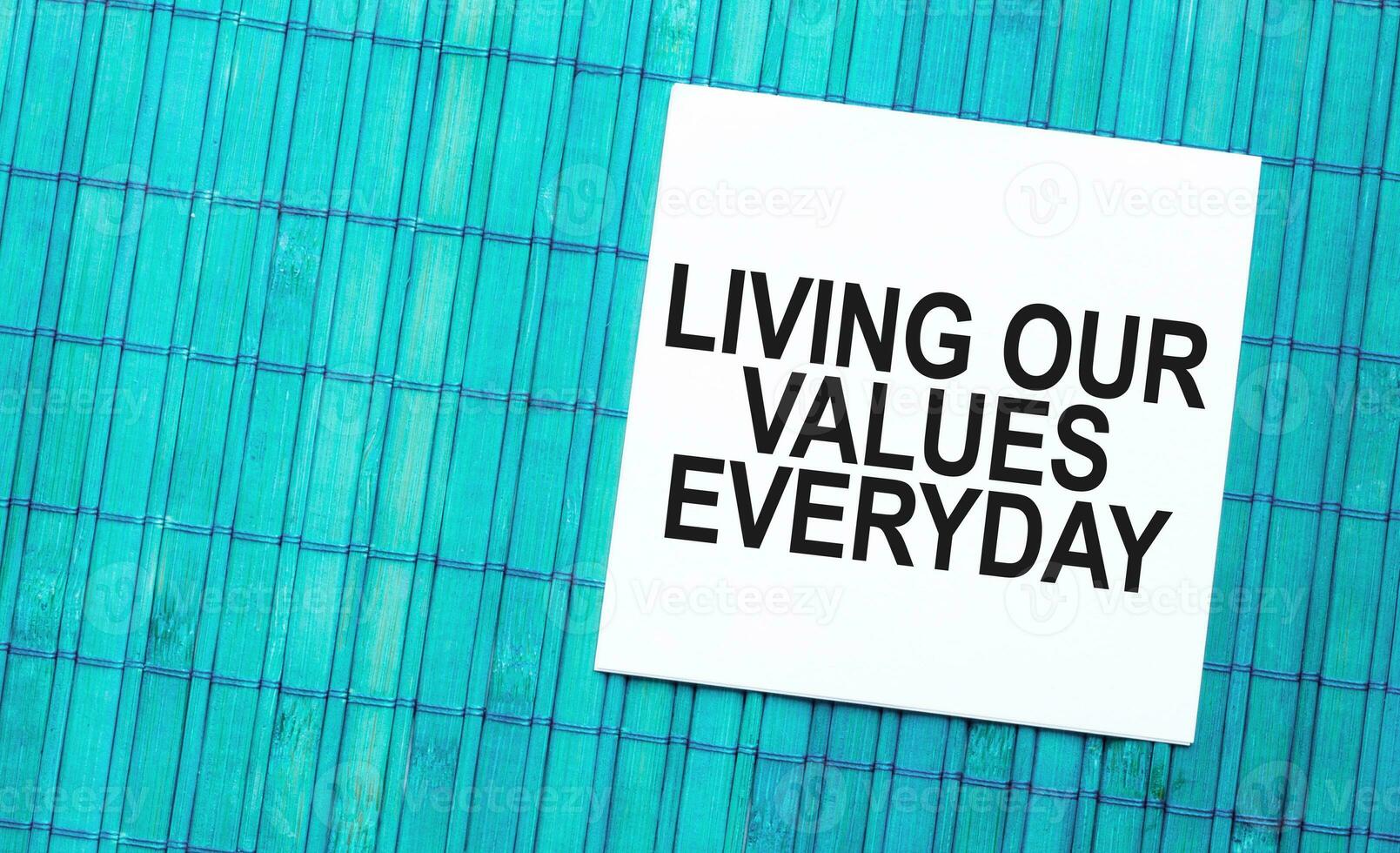 blank note pad with text living our values everyday on green wooden background photo