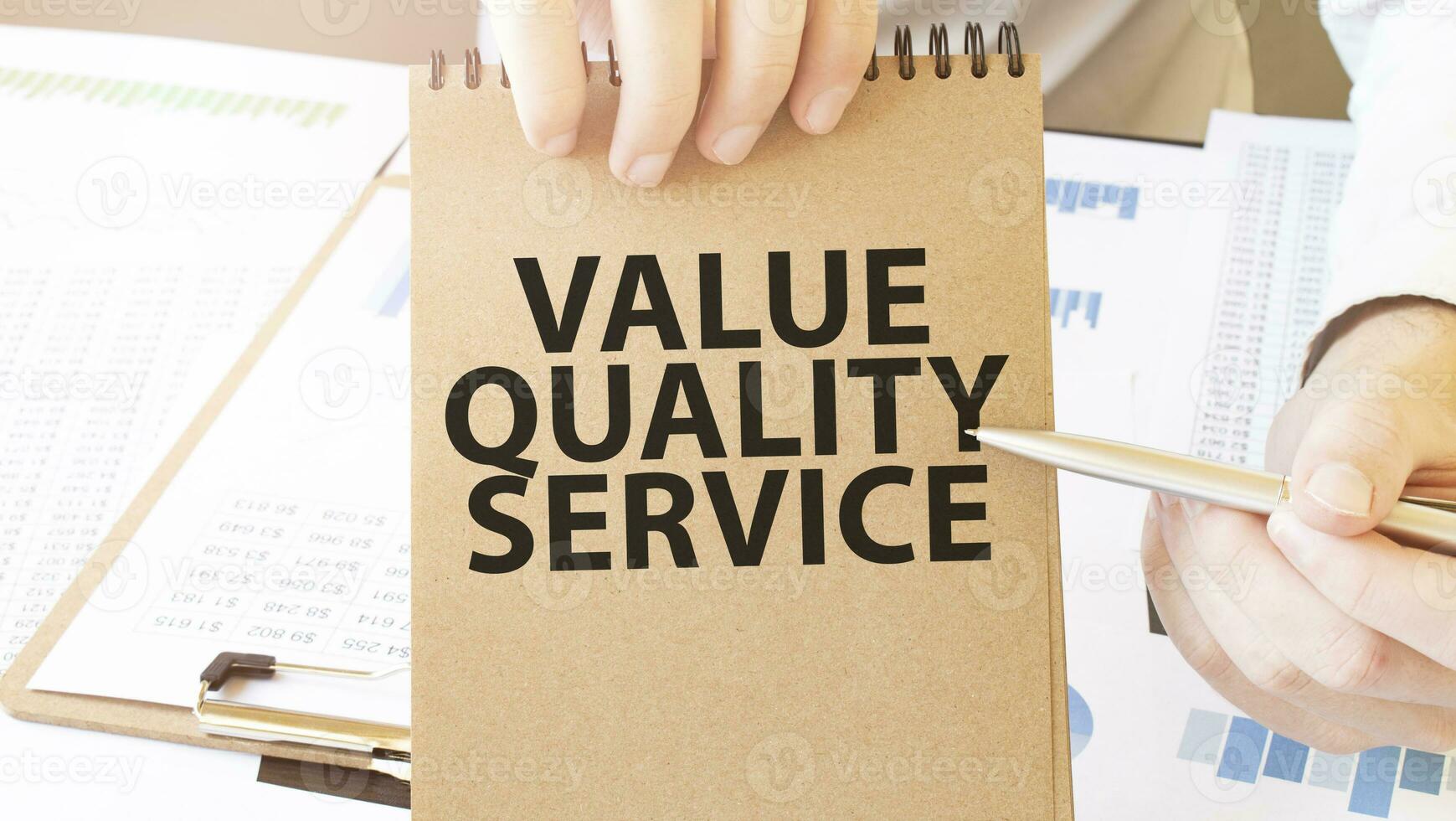 texto valor calidad Servicio en marrón papel bloc en empresario manos en el mesa con diagrama. negocio concepto foto