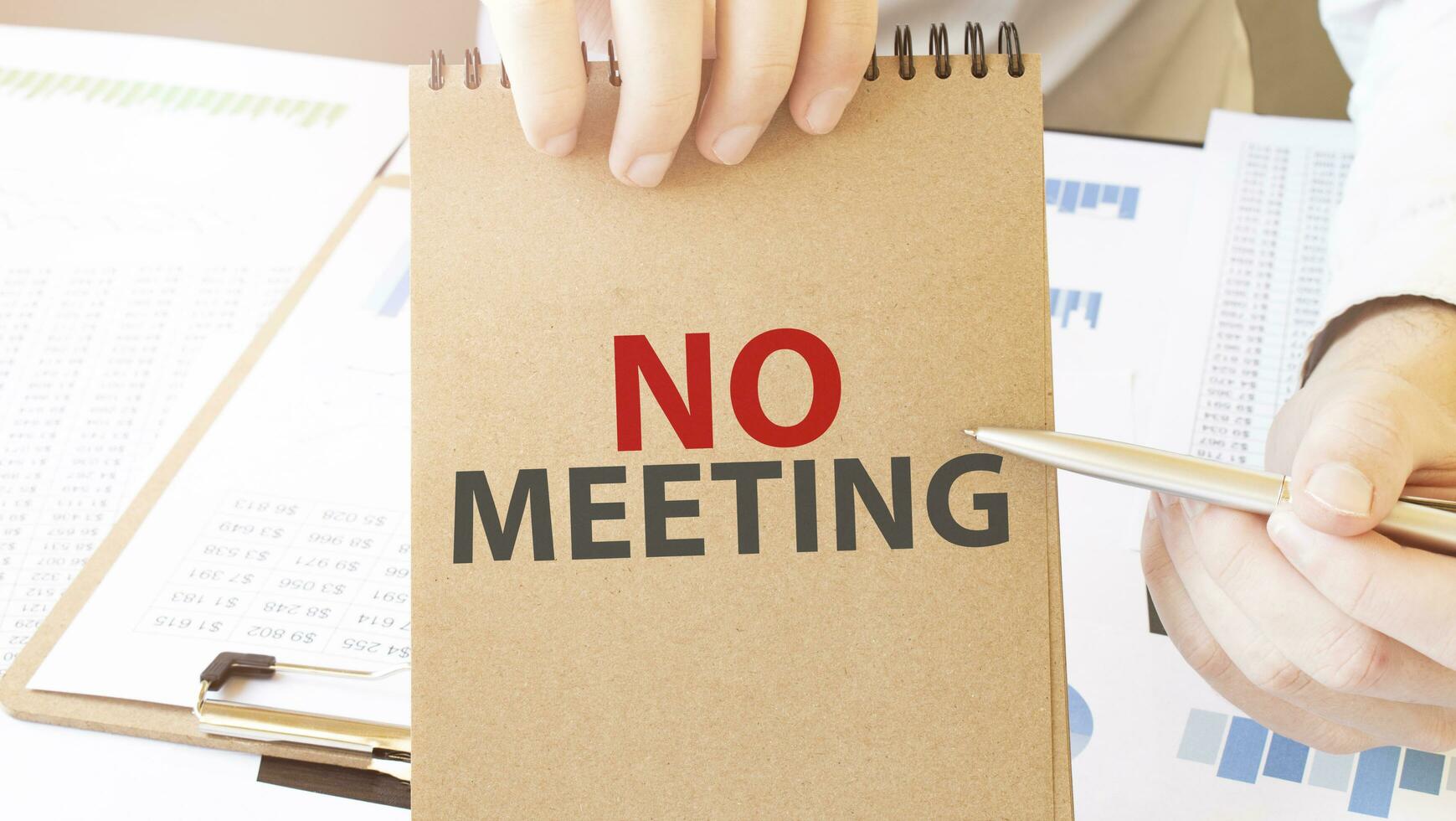Text no meeting on brown paper notepad in businessman hands on the table with diagram. Business concept photo