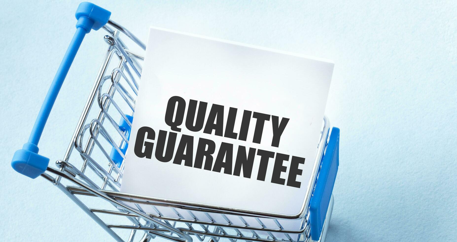Shopping cart and text quality guarantee on white paper note list. Shopping list concept on blue background. photo