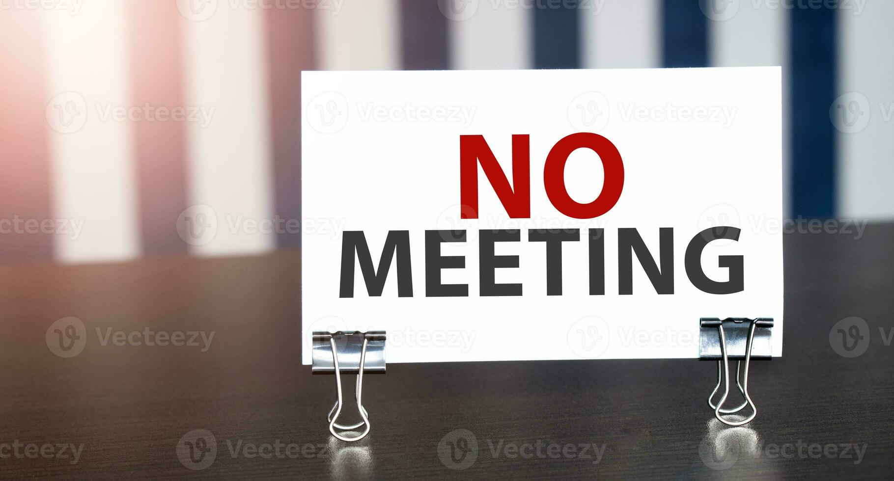 no meeting sign on paper on dark desk in sunlight. Blue and white background photo