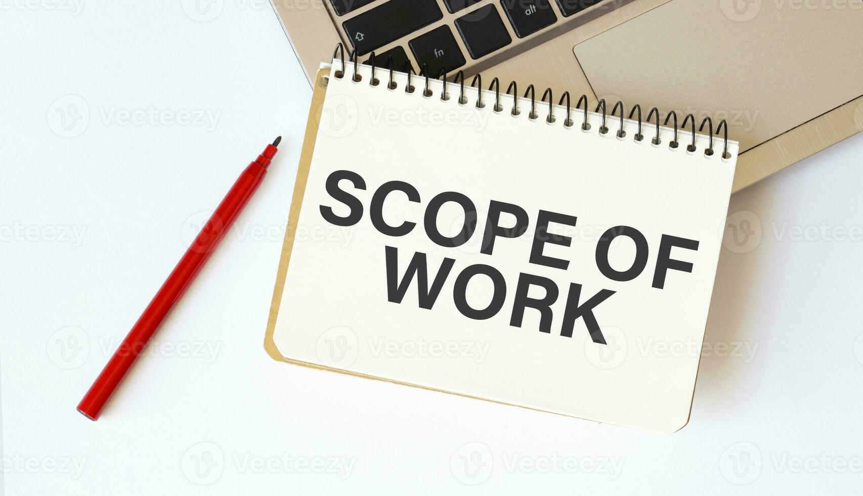 Laptop, red pen and notepad with text scope of work in the white background photo