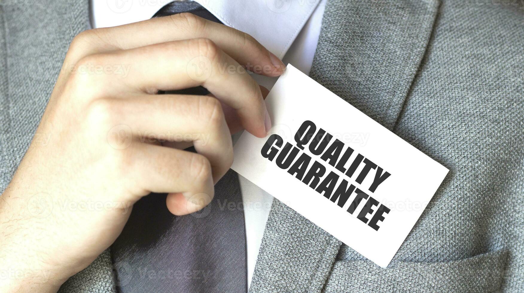 Businessman putting a card with text quality guarantee in the pocket photo