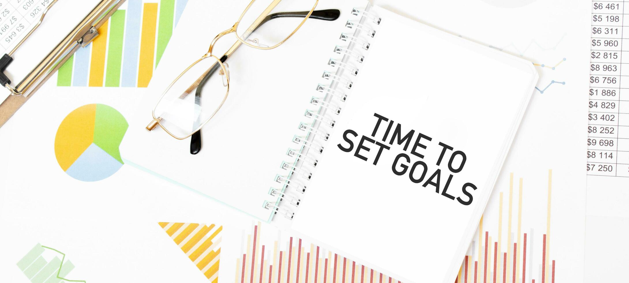 Text TIME TO SET GOALS on white notepad, glasses, graphs and diagrams. photo