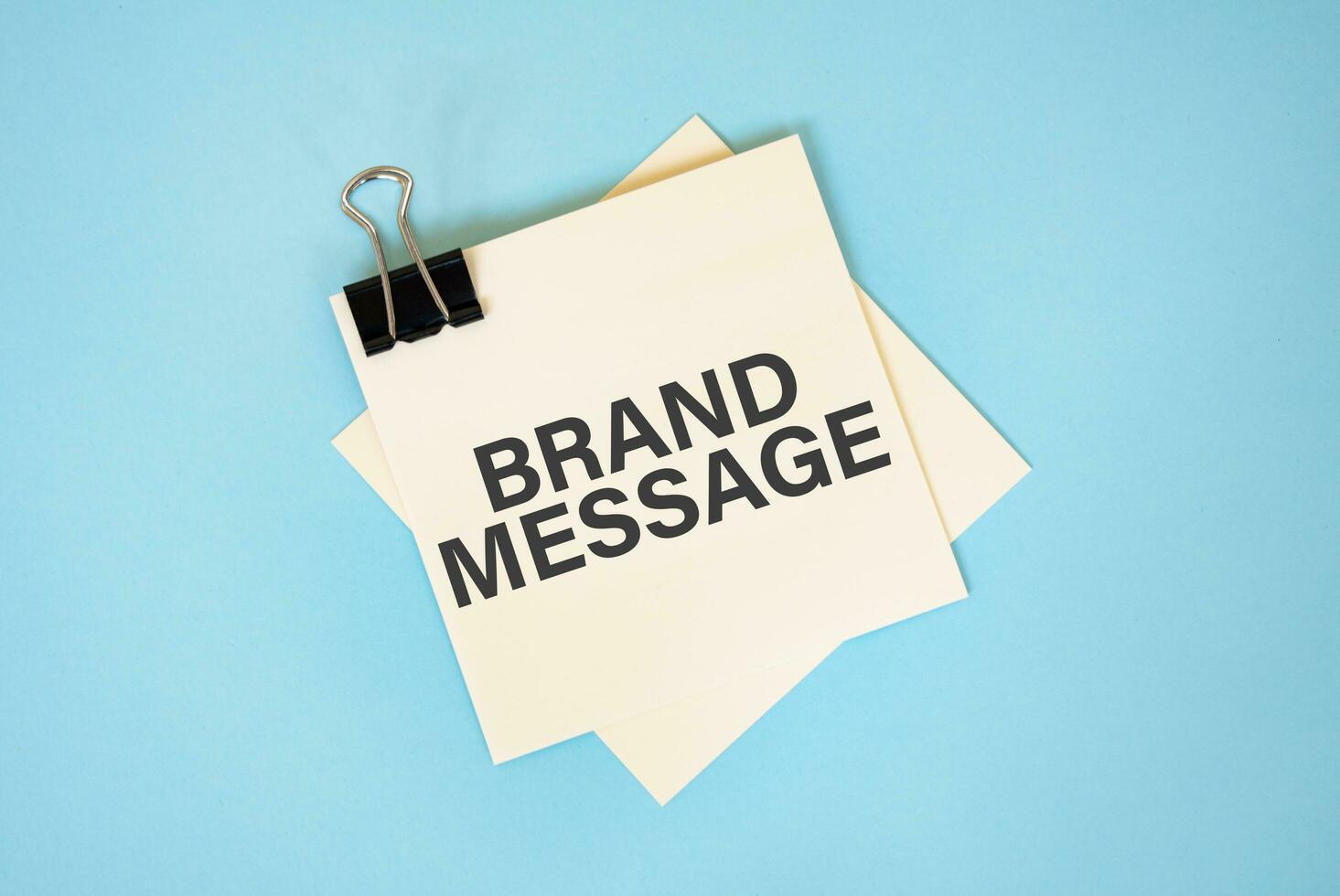 Text BRAND MESSAGE on sticky notes with copy space and paper clip isolated on red background.Finance and economics concept. photo