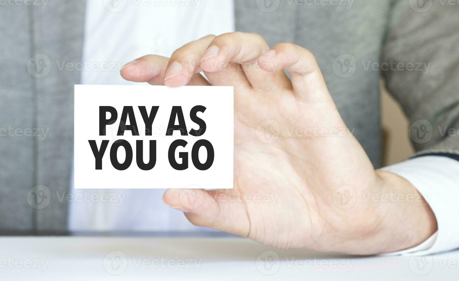 Businessman holding a card with text pay as you go photo