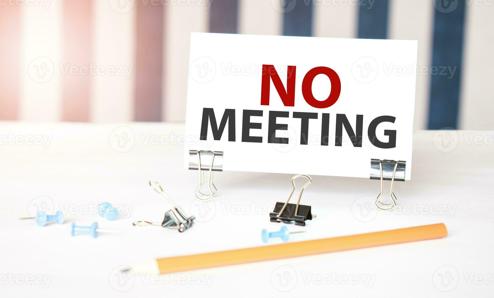 no meeting sign on paper on white desk with office tools. Blue and white background photo