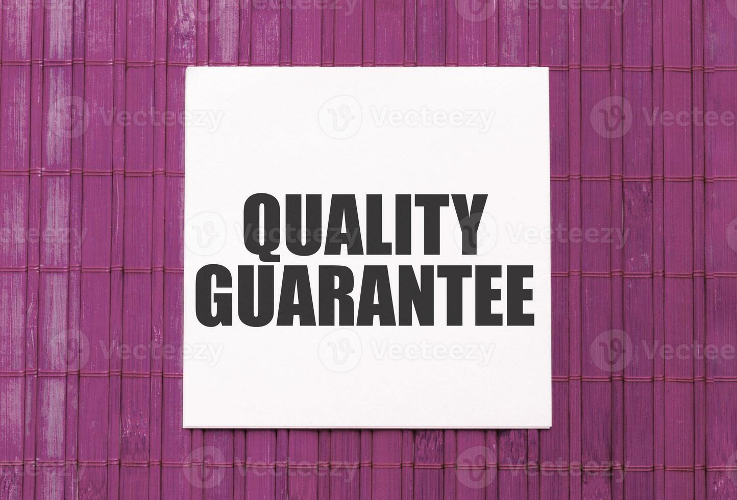 blank note pad with text quality guarantee on blue wooden background photo