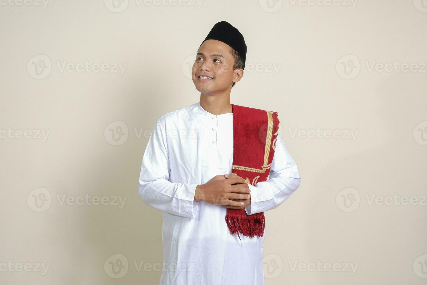Portrait of attractive Asian muslim man in white shirt feeling confident, smiling and looking at camera. Isolated image on gray background photo
