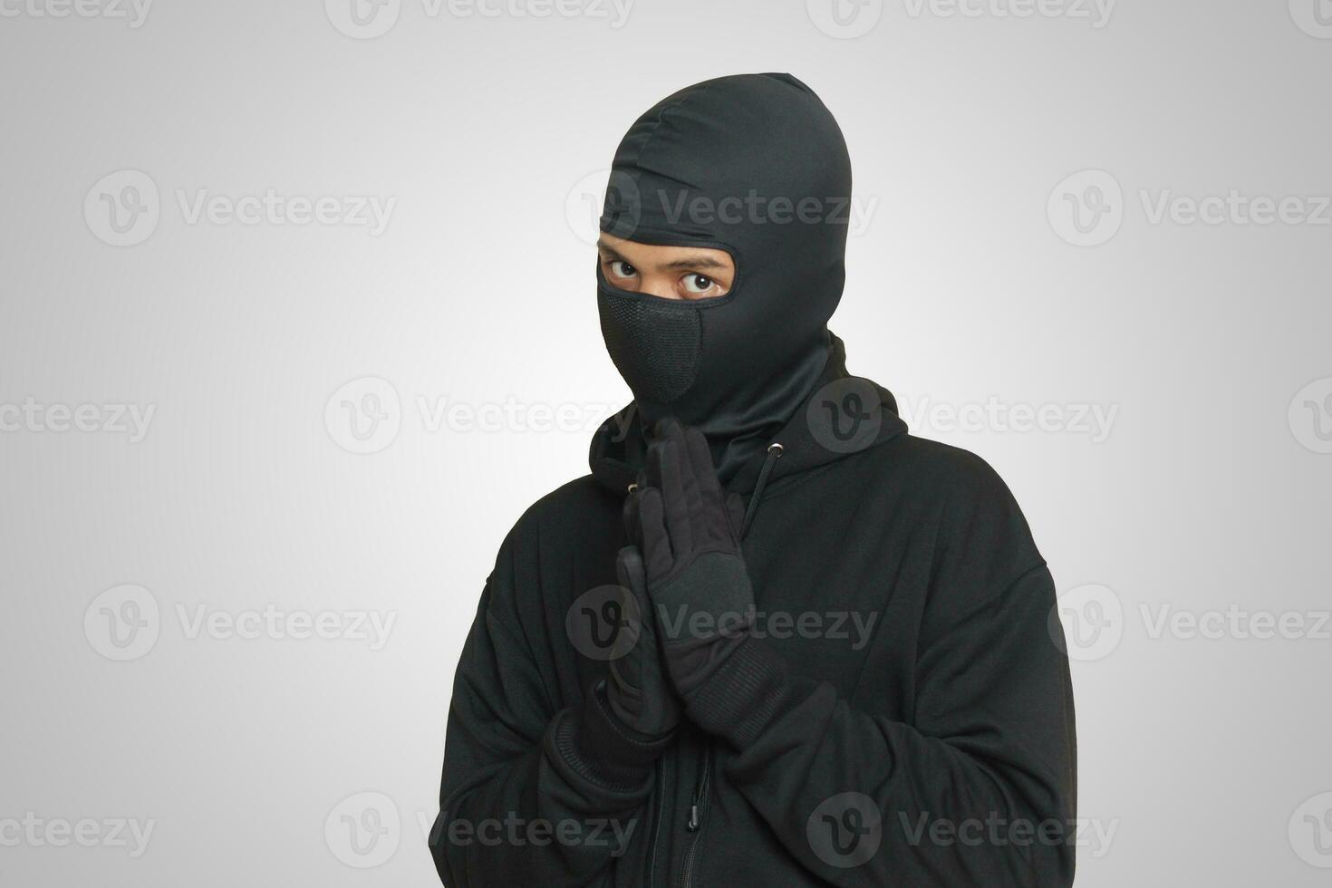 Mysterious man wearing black hoodie standing and looking at camera. Isolated image on gray background photo