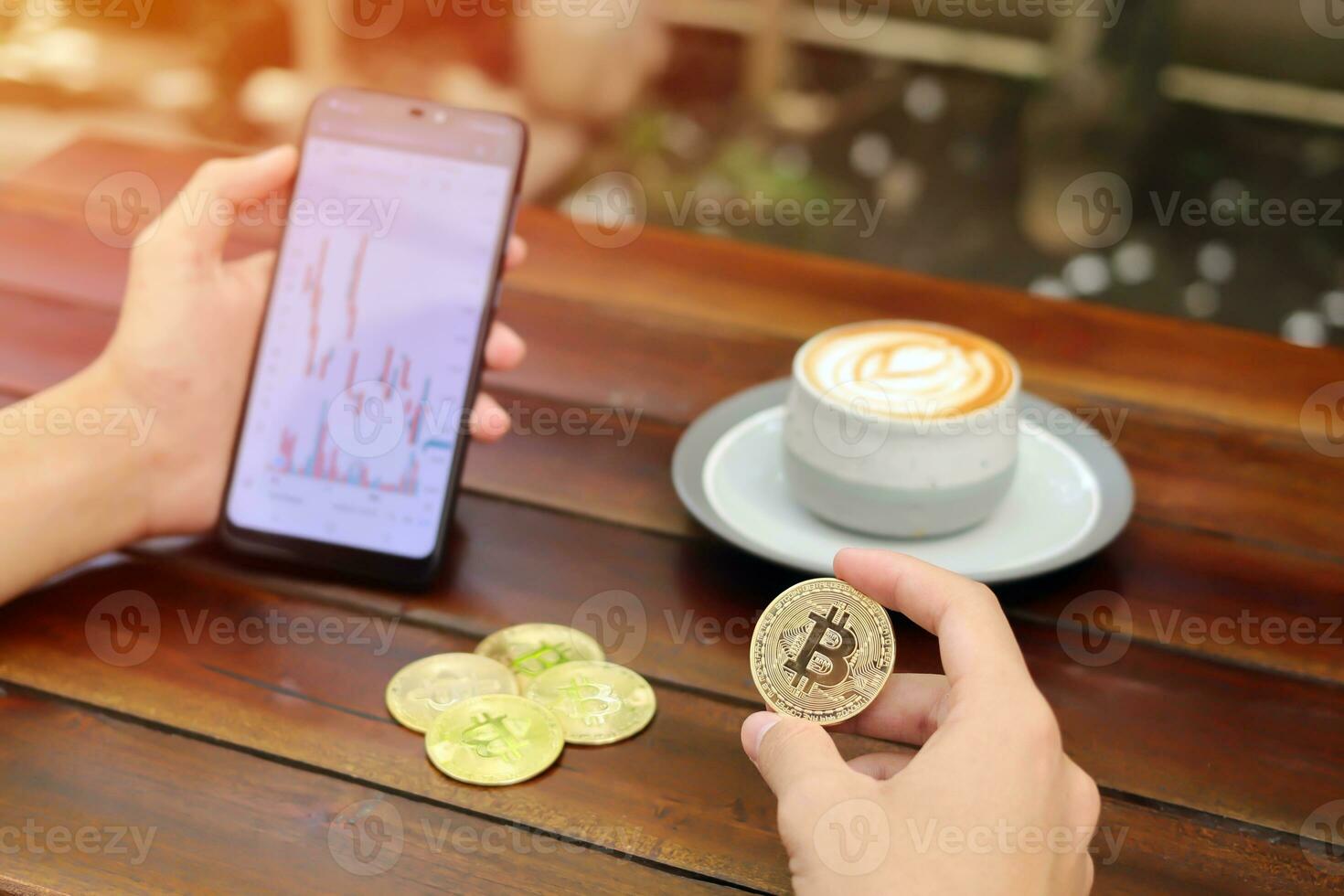 Close up of male hand holding bitcoin and mobile phone with candlestick chart on screen. Cryptocurrency trading concept photo