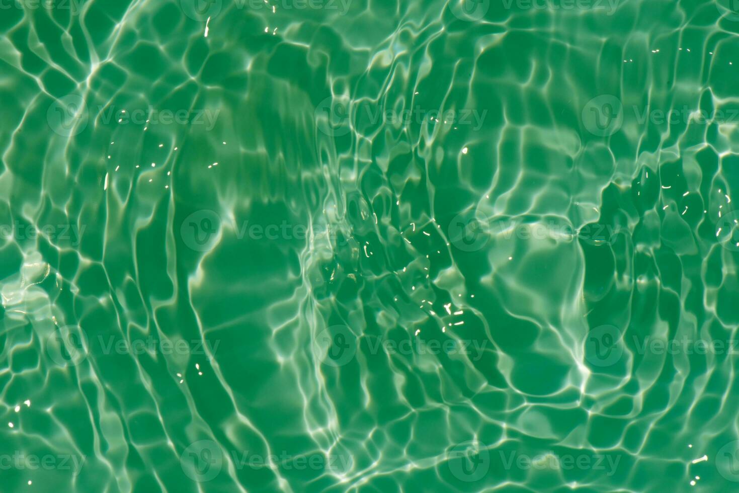 Green water with ripples on the surface. Defocus blurred transparent blue colored clear calm water surface texture with splashes and bubbles. Water waves with shining pattern texture background. photo