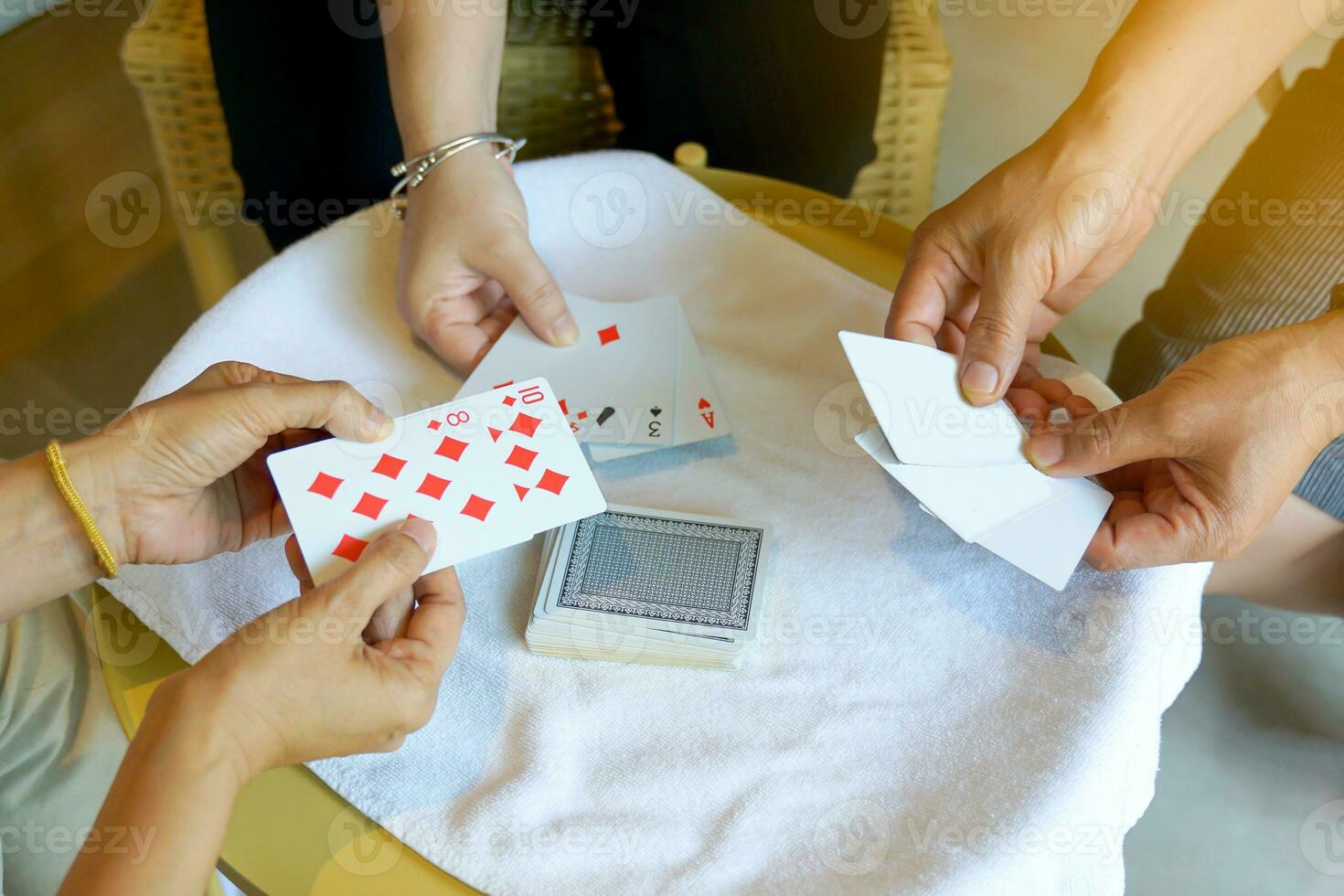 Group of Asian friends playing card games for fun in a hostel during their free time while traveling together.soft and selective focus. photo