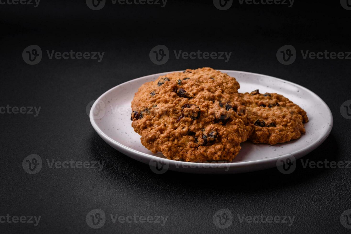 Delicious baked oatmeal raisin cookies on a dark concrete background photo