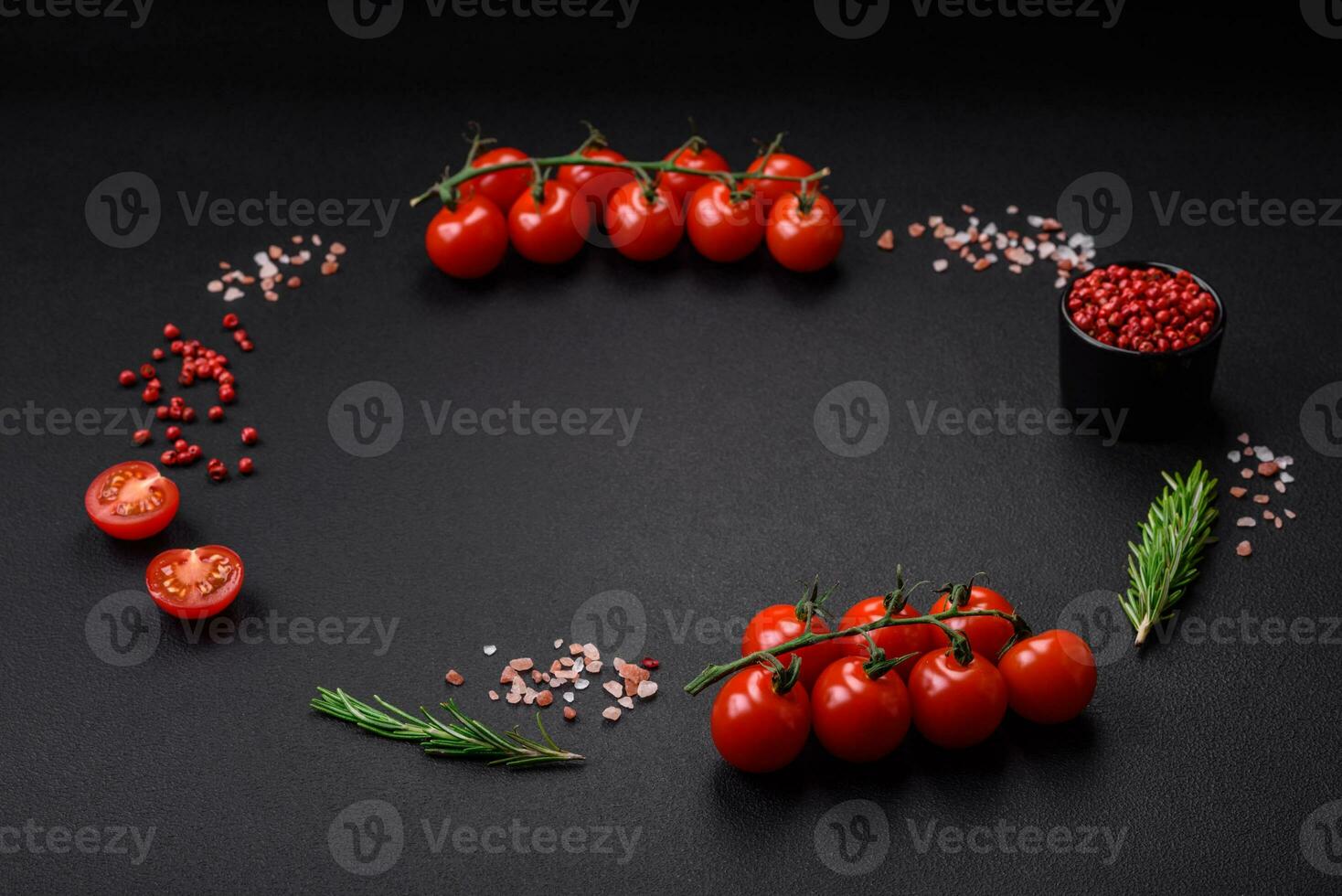 Empty black texture table, cherry tomatoes on a twig, spices, salt and herbs photo
