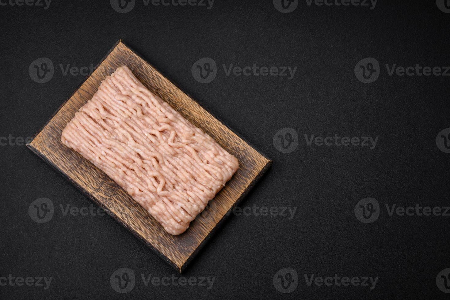 Fresh minced chicken with salt, spices and herbs on a wooden cutting board photo