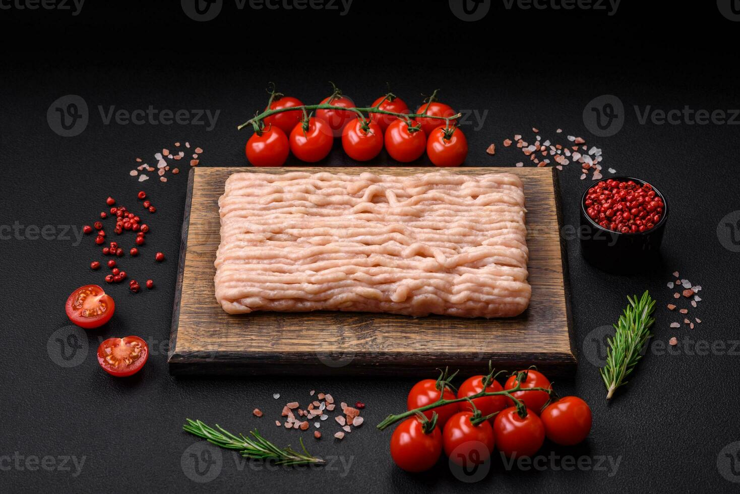 Fresh minced chicken with salt, spices and herbs on a wooden cutting board photo